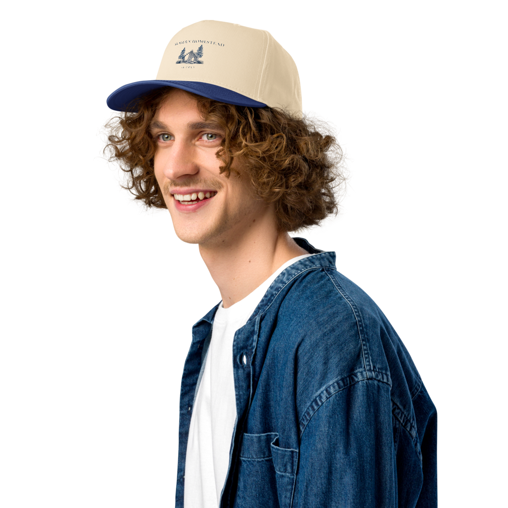 Man wearing a beige and blue cap with a denim jacket and white shirt on a white background