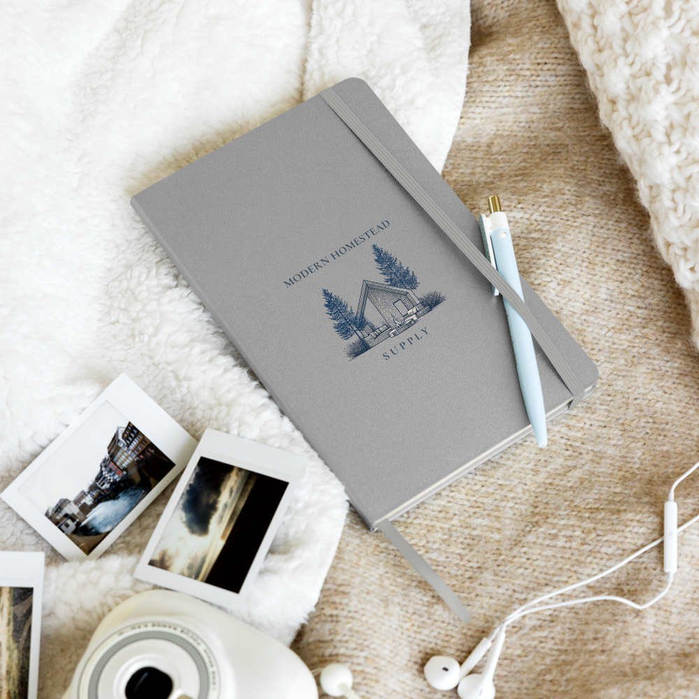 Gray notebook with a logo on a textured surface with photos and earbuds.